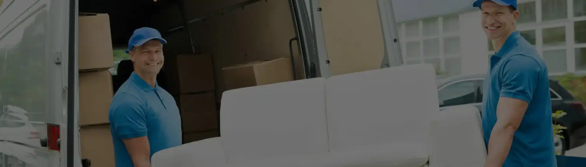 Weiße Couch wird von zwei Möbelpackern in einen LKW verladen